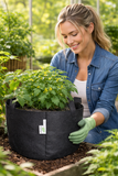 Woman in a garden holding a black fabric pot with plants